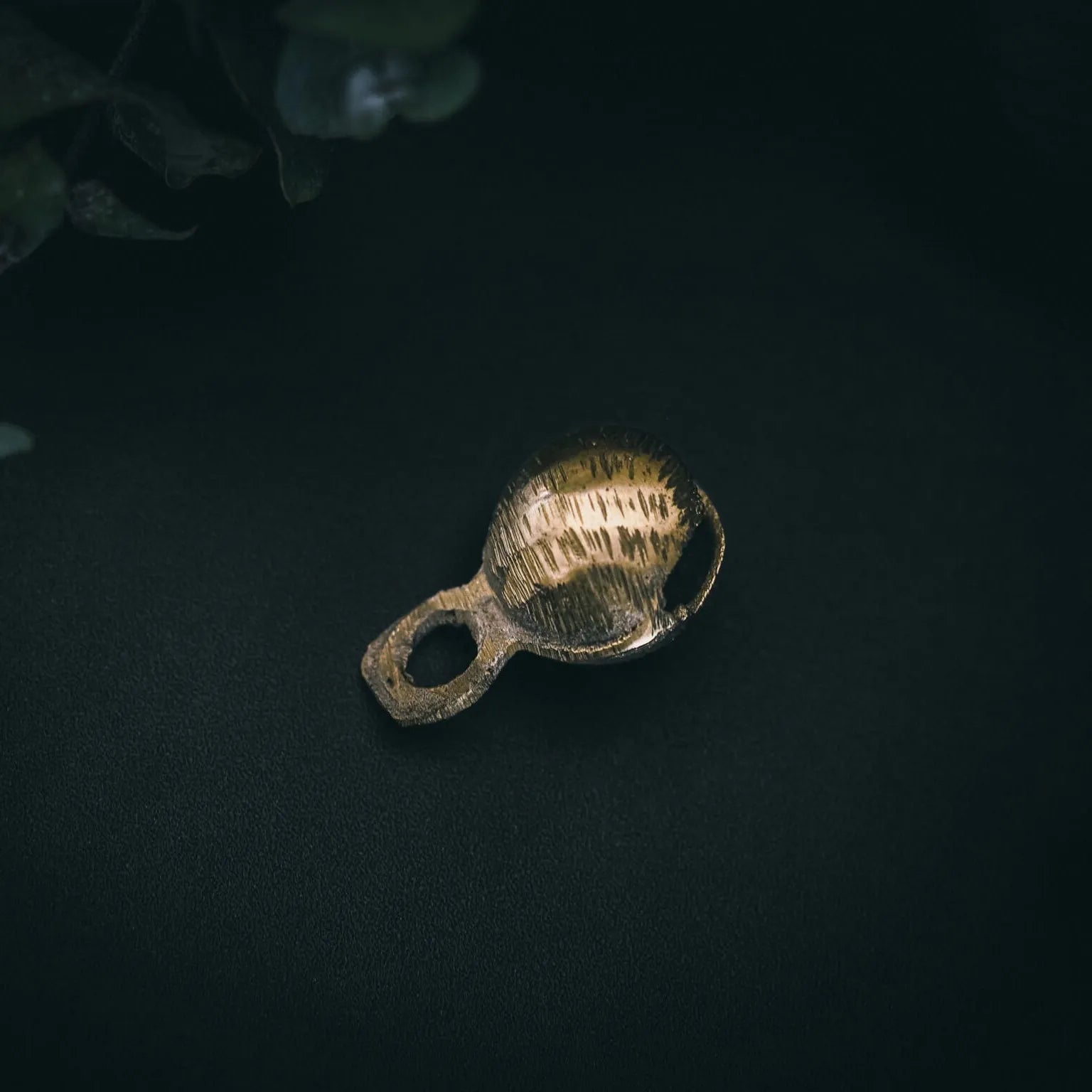 Närbild av mässingbjällra Rispig-variant som visar detaljer av fint graverat radialt mönster på kullrig yta