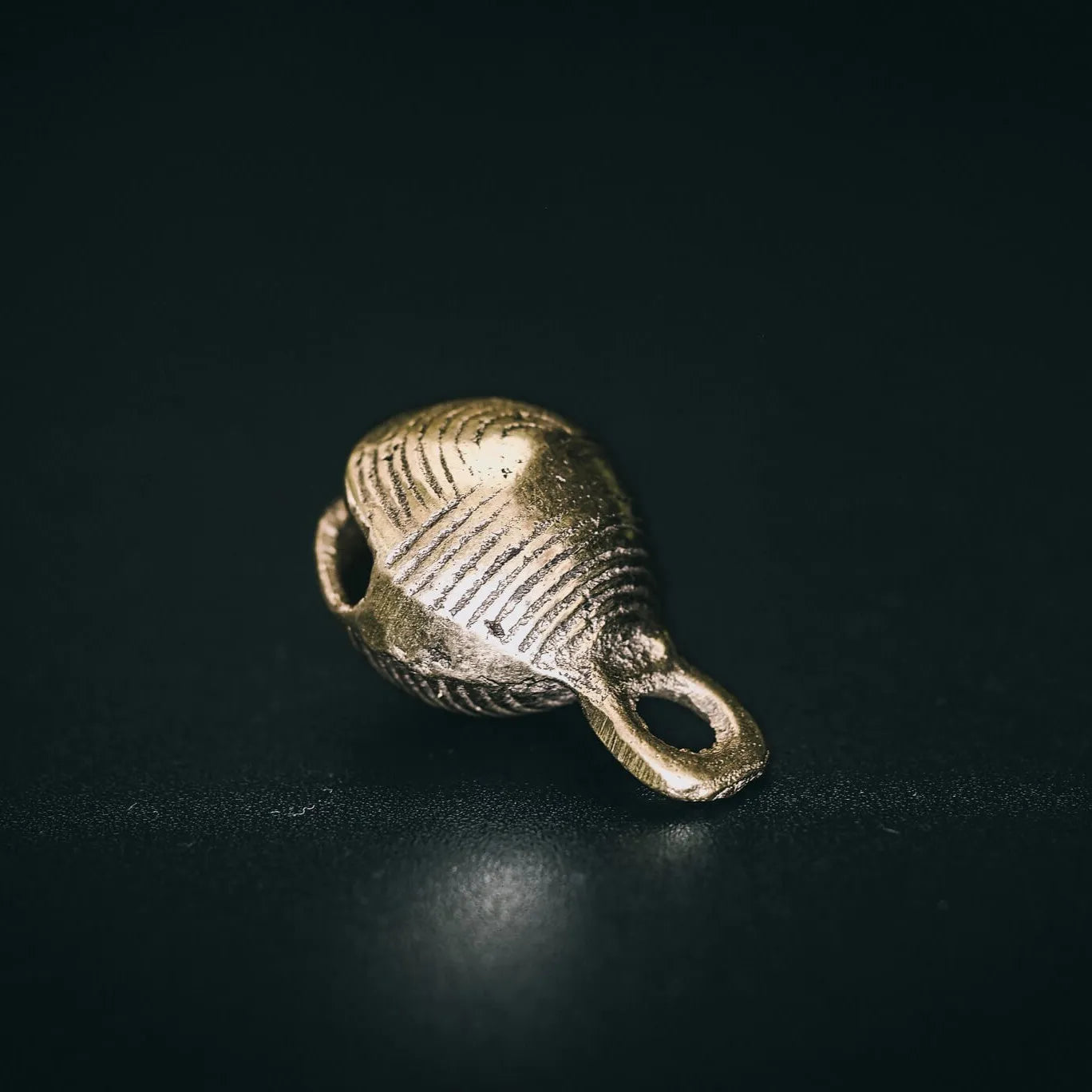 Mässingbjällra Rispig i perspektivvinkel som visar helt form med tydlig öppning i botten och radialgräverad ytterytor