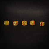 Fem gula kubiska glaspärlor i rad mot mörk bakgrund, varje med röd ränds, visar handgjord glasstruktur och 1mm håll