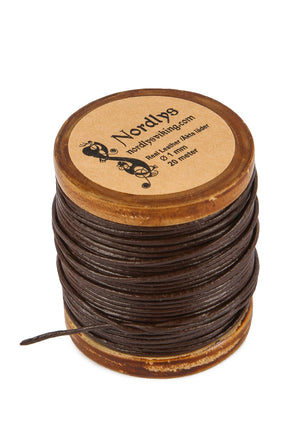 Läderband brun 1mm 20m - mörkt brunt lädersnöre tätt lindade på träspole med naturlig ljus trä och graverad etikett. Skadat på vit bakgrund i studiomiljö.