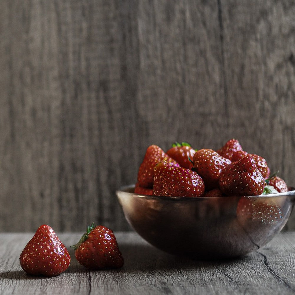 Natural oxhorn bowl filled with fresh strawberries, demonstrating durable use for serving organic produce. Bowl shows natural grain pattern and sustainable material