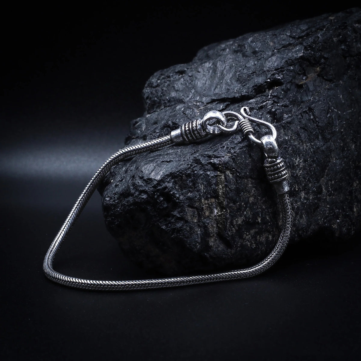 Silverpläterad mässingarmband med ormhuvudstängning och fin kedjestruktur, fotograferat professionellt för att visa Nordens mytologiska serpent-motiv