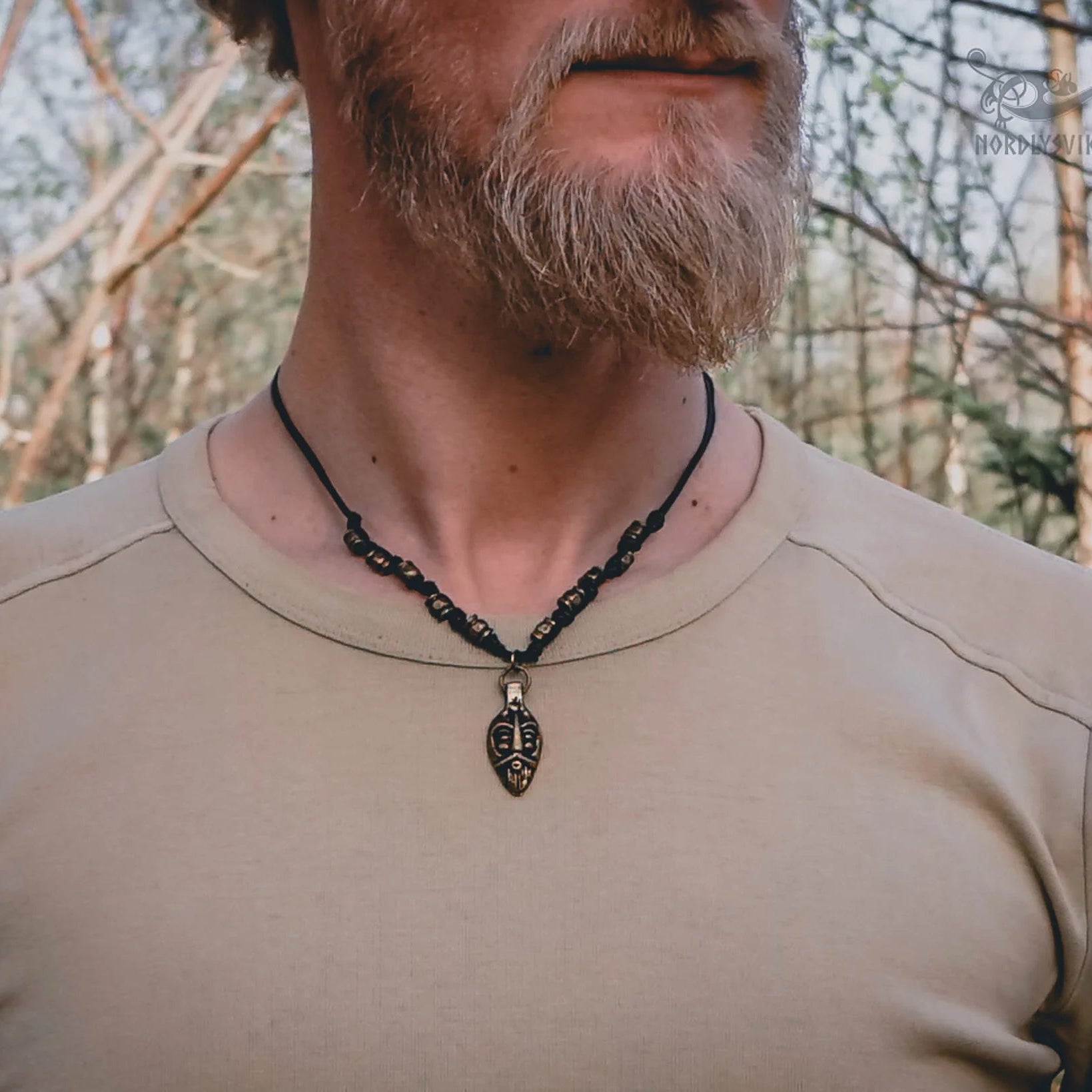 Odin halsband i brons på svart läderband, visat på person i naturmiljö