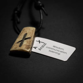 Handgjord runhalsmycke med Ansuz-runan i oxben på svart läderrem. Vit informationskort visar runans betydelse: Visdom, Amulti, kommunikation, lyssnande. Traditionellt vikingainspirerat smycke med betydelsebeskrivning.