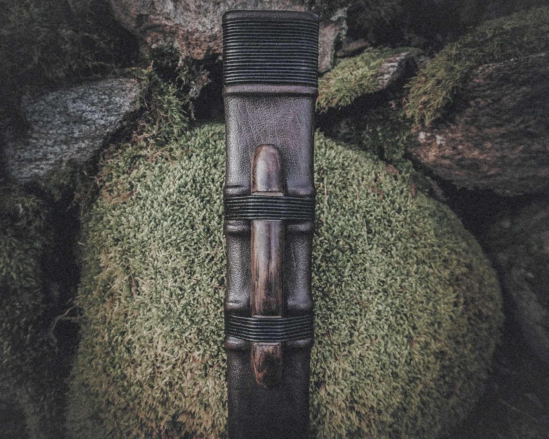 Närbild av svärdskida 'Black Ice' visar läderband, koppling och mässingsmontage mot naturlig bakgrund