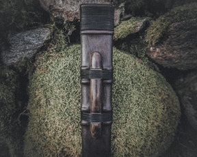 Närbild av svärdskida 'Black Ice' visar läderband, koppling och mässingsmontage mot naturlig bakgrund