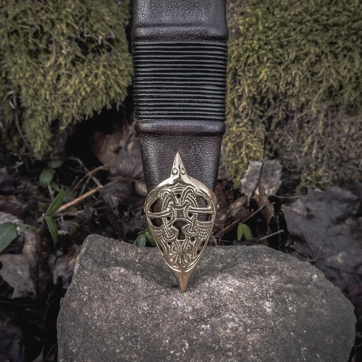 Svärdskida 'Black Ice' med ornamental mässingsmontage och keltisk flätningsmönster på naturlig berggrund