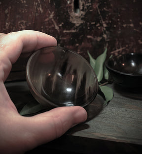 Hand holding polished dark horn bowl showing glossy finish and craftsmanship detail
