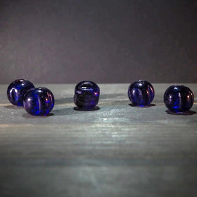 Blå melonpärlor i glas. Fyra kulor med mörkblå till violett färg. Pärlorna visar naturlig färgvariation och metalliska reflektioner. Material: glas. Användning: pärlor för smycken och armband.