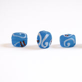 Tre kubformade blå glaspärlor med vita spiraler och terrakottadetaljer, matt finish, Norrköping-gravfynd