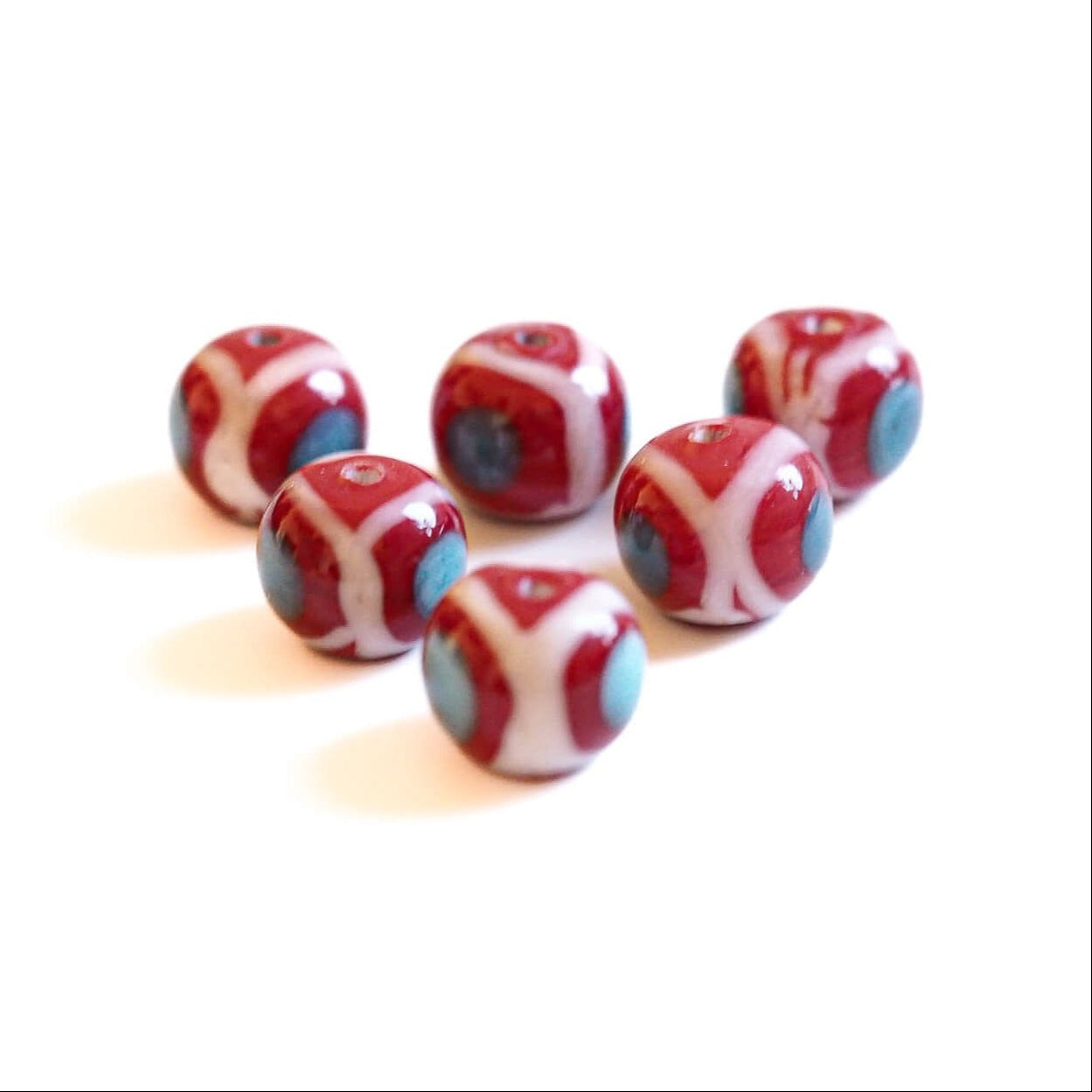Red glass bead with white and blue-gray decorative pattern, shiny finish, approximately 14-18mm diameter, Viking-era inspired design