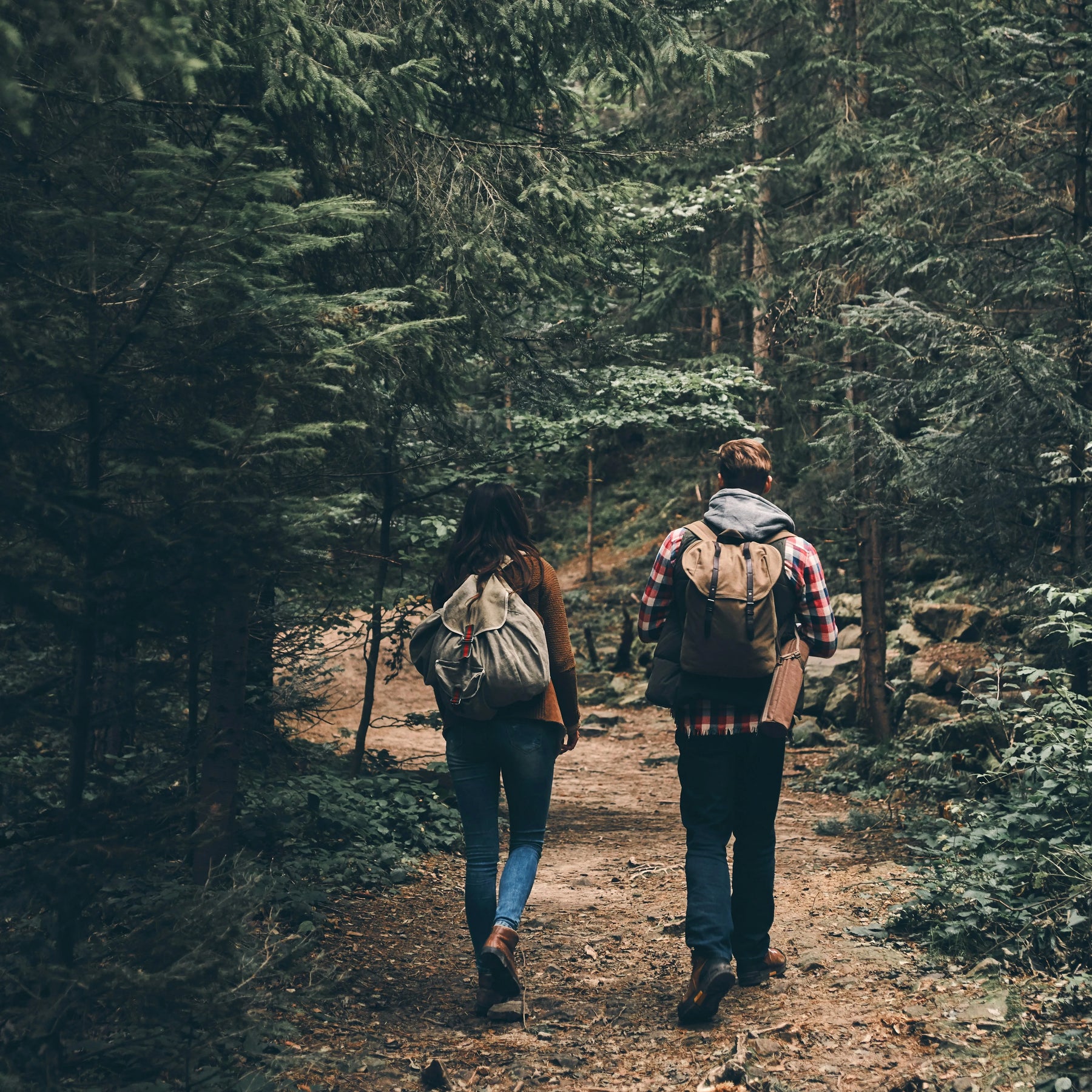 Två vandrare på skogsstig med ryggsäckar, visar visselpipan i naturlig användning under Nordic vandringsabventyrs