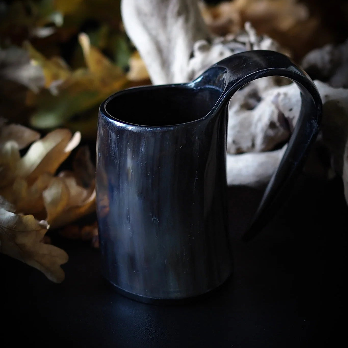 Dark horn espresso mug in natural outdoor setting with botanical background, emphasizing Viking lifestyle aesthetic