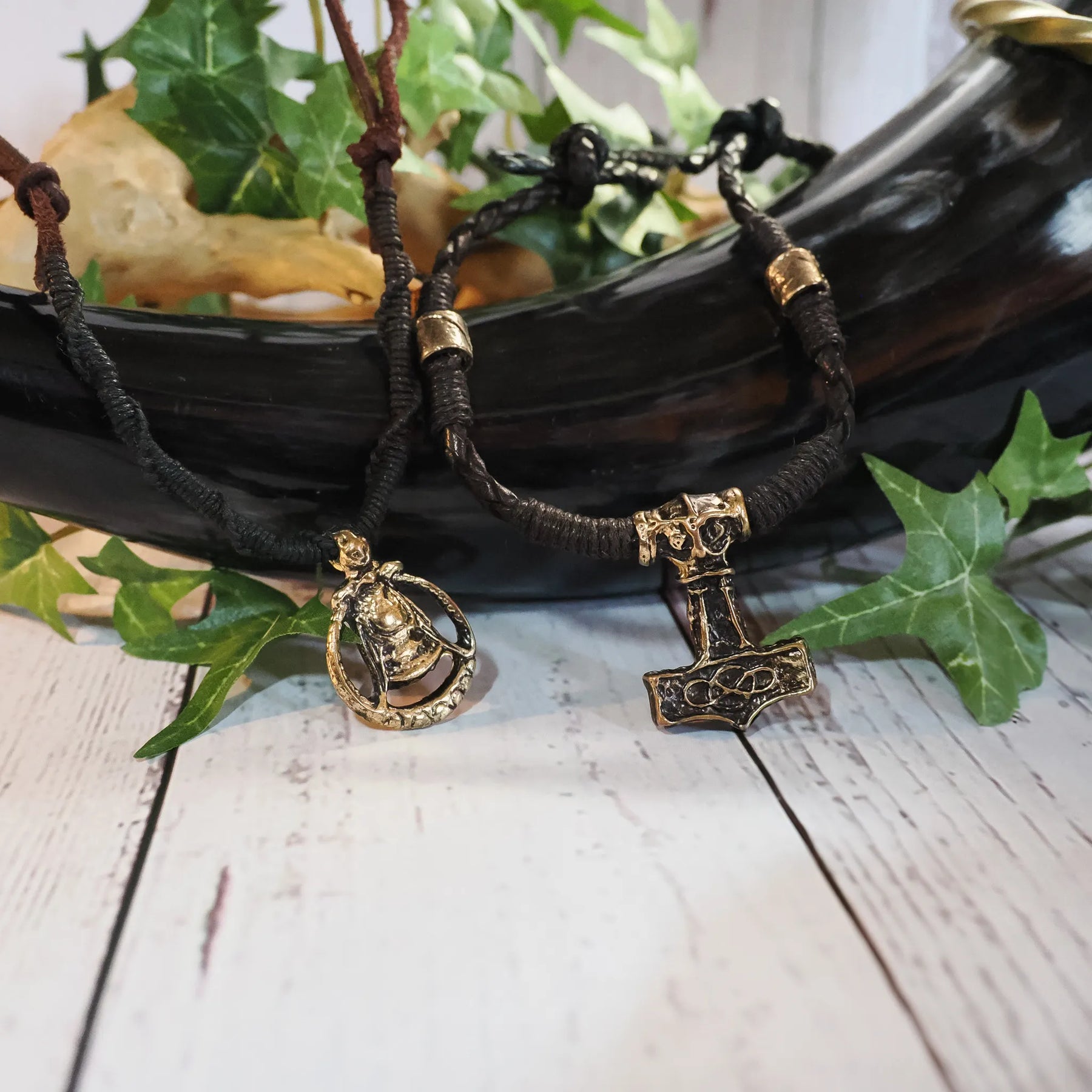 Vikingbröllopspakets smycken - läderarmband och hårperler med Mjölnir- och Freja-anhängar, ordnade på vit träyta