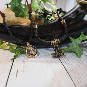 Vikingbröllopspakets smycken - läderarmband och hårperler med Mjölnir- och Freja-anhängar, ordnade på vit träyta