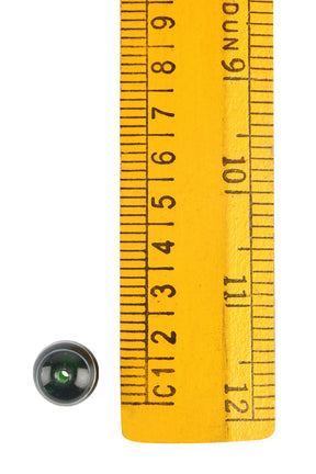 En grön glaspärla med vita dekorlinjer framför måttstock för att visa storlek, cirka 10-12mm diameter