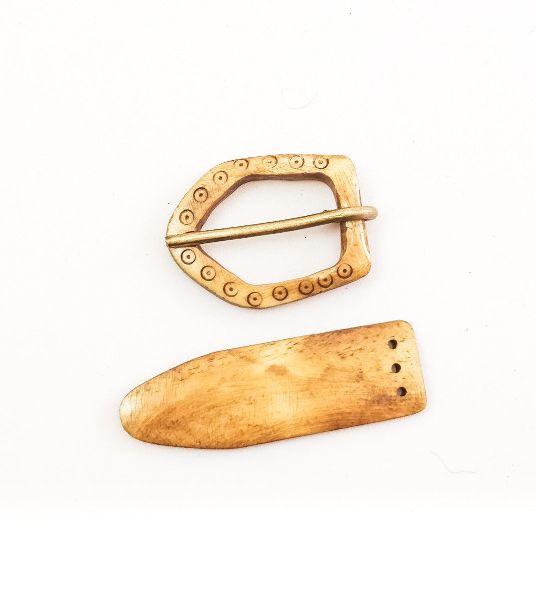 Bältesspänne i ben på vit bakgrund: D-formad spänne med prydnadsrand och mässingsnål tillsammans med bältesende med tre fästhål