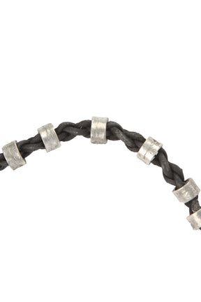 Närbild på svart vävsad läderarmband med silverpärlor och ögla-knappslutning. Handgjord vikingaarmband.