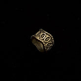 Elmar brass beard bead in three-quarter rotation displaying oval relief pattern and rope-trimmed rim edges