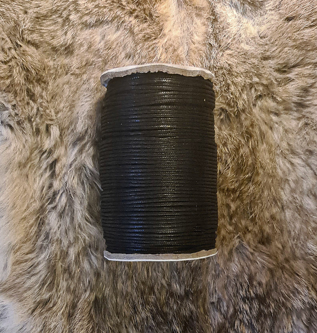 Vaxad svart bomullstråd 2mm på naturlig texturerad bakgrund.