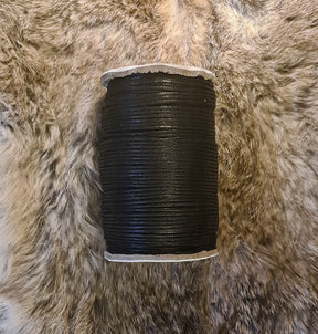 Vaxad svart bomullstråd 2mm på naturlig texturerad bakgrund.