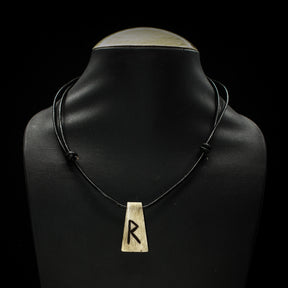 Handgjord halsband av oxben med Raidho-runan på svart lädersnöre, visat på mannekängbålen.