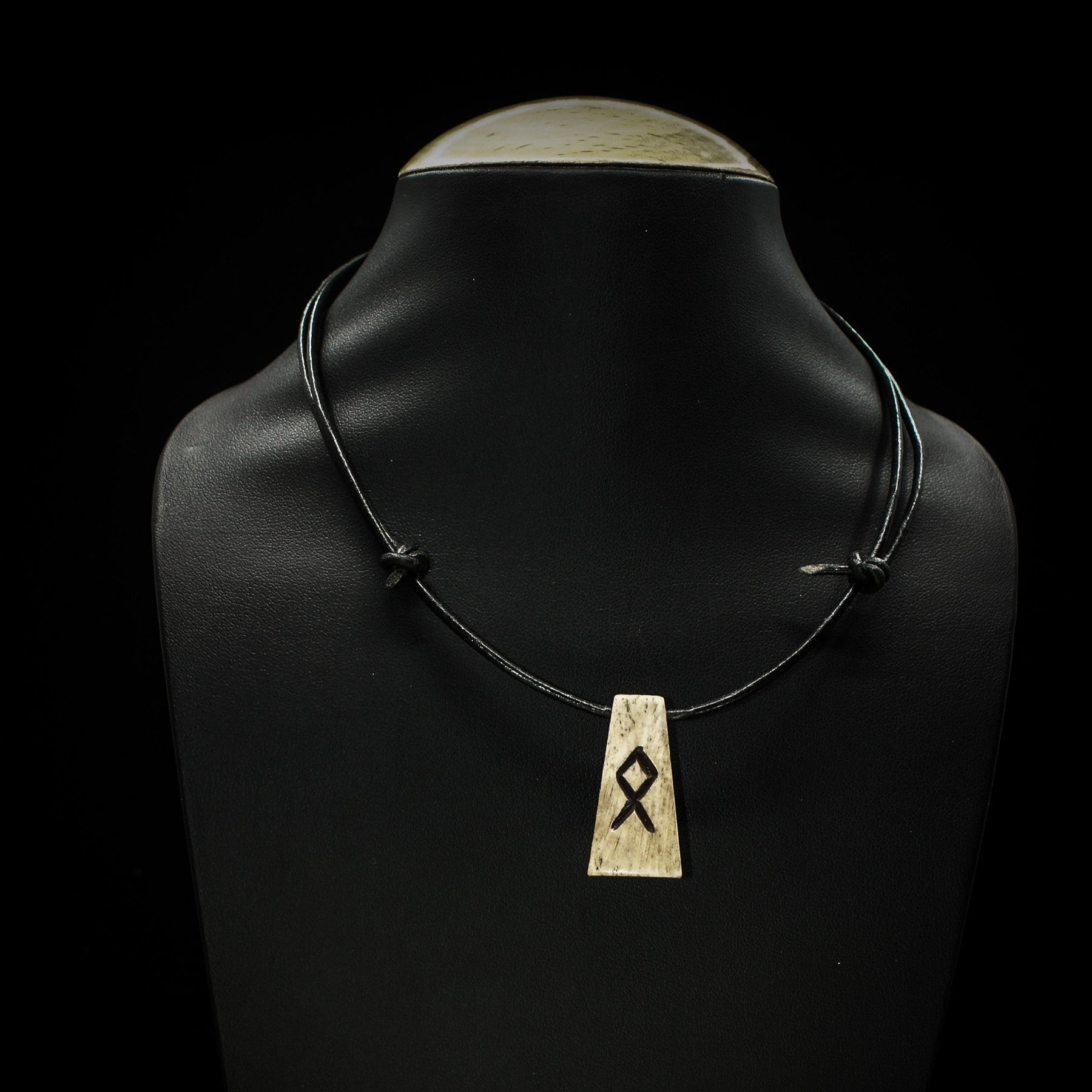 Nordiska Runor i ben-halsband på svart lädersnöre med Othala-runan på mannekäng, visar produktens naturliga benstruktur och hängande längd.