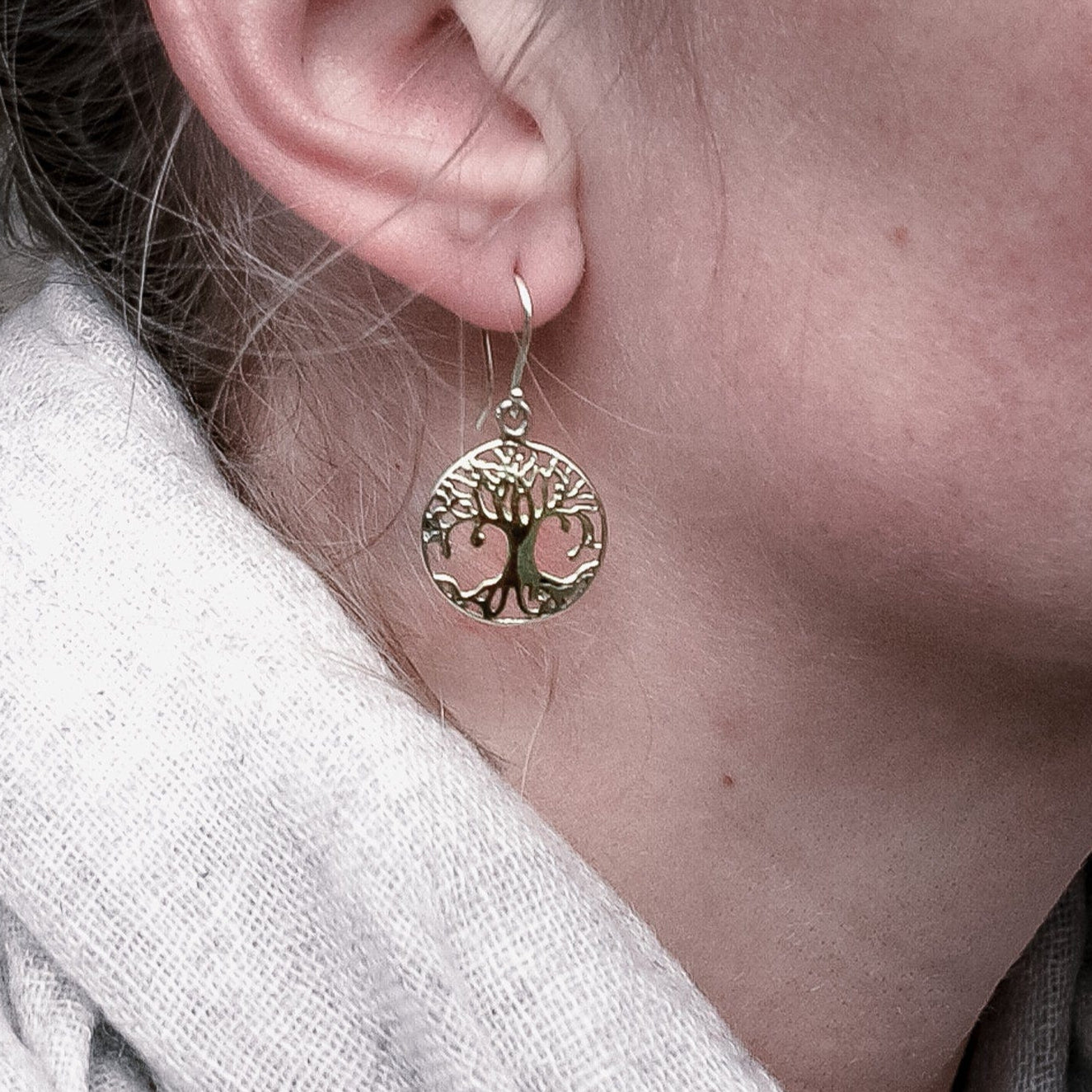 Yggdrasil örhängen i guldtonat handgjord mässing, livsträdsdesign med keltiska detaljer, visade på öra