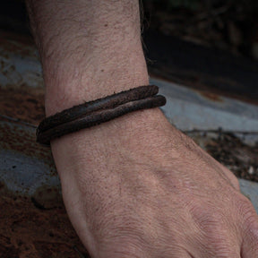 Galar vikingaarmband av läder på mans handled mot naturlig bakgrund