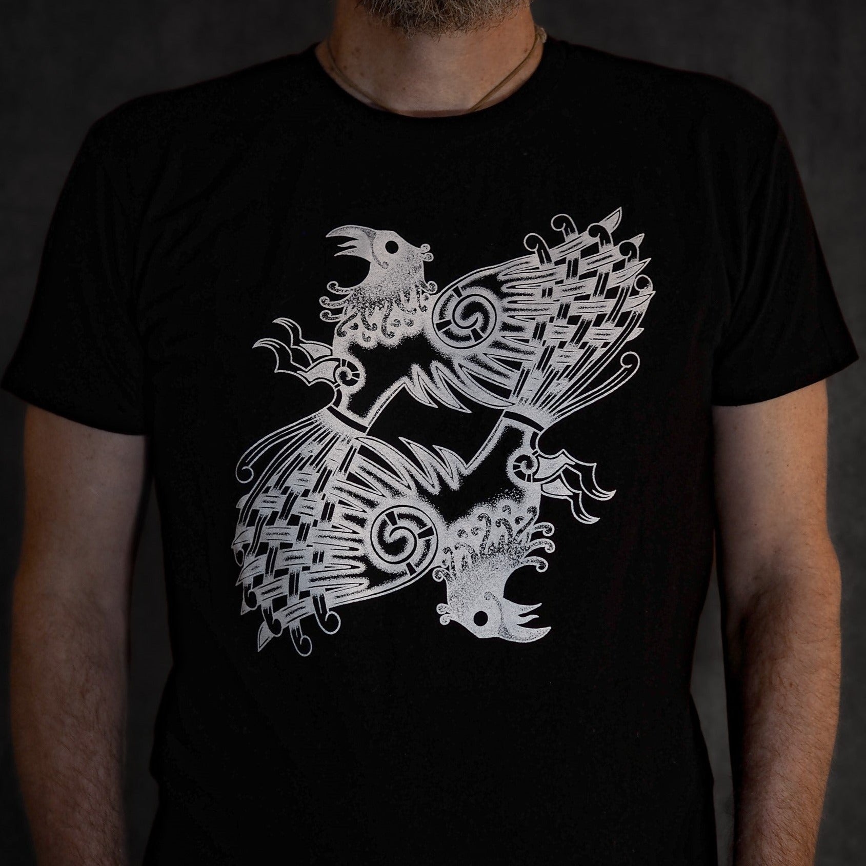 Sort t-shirt med hvidt grafisk design af Huginn og Muninn - Odins to ravne - i vikingestil med keltisk knudeværk og nordiske spiralmønstre