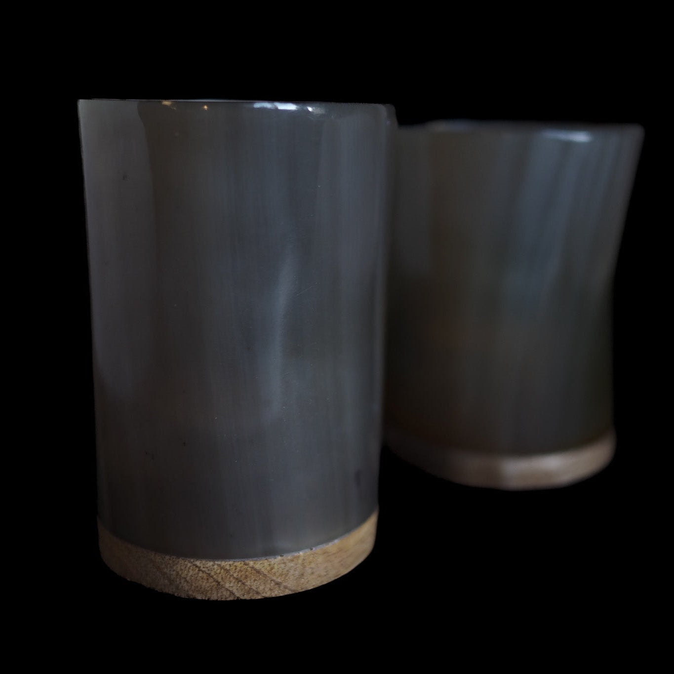 Två hornljuslyktor utan tänd ljus, visar tydligt den regelbundna mönstringen av hjärtformade hål i organiskt horn. Naturliga kornstrukturer och varma bruntoner synliga.