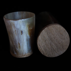 Två komponenter av bockhornsljuslyktan: på vänster sida den polerade hornhylsan med naturliga nyänser, på höger sida den rundrunda träbasen. Produktuppställning sedd från sidan.