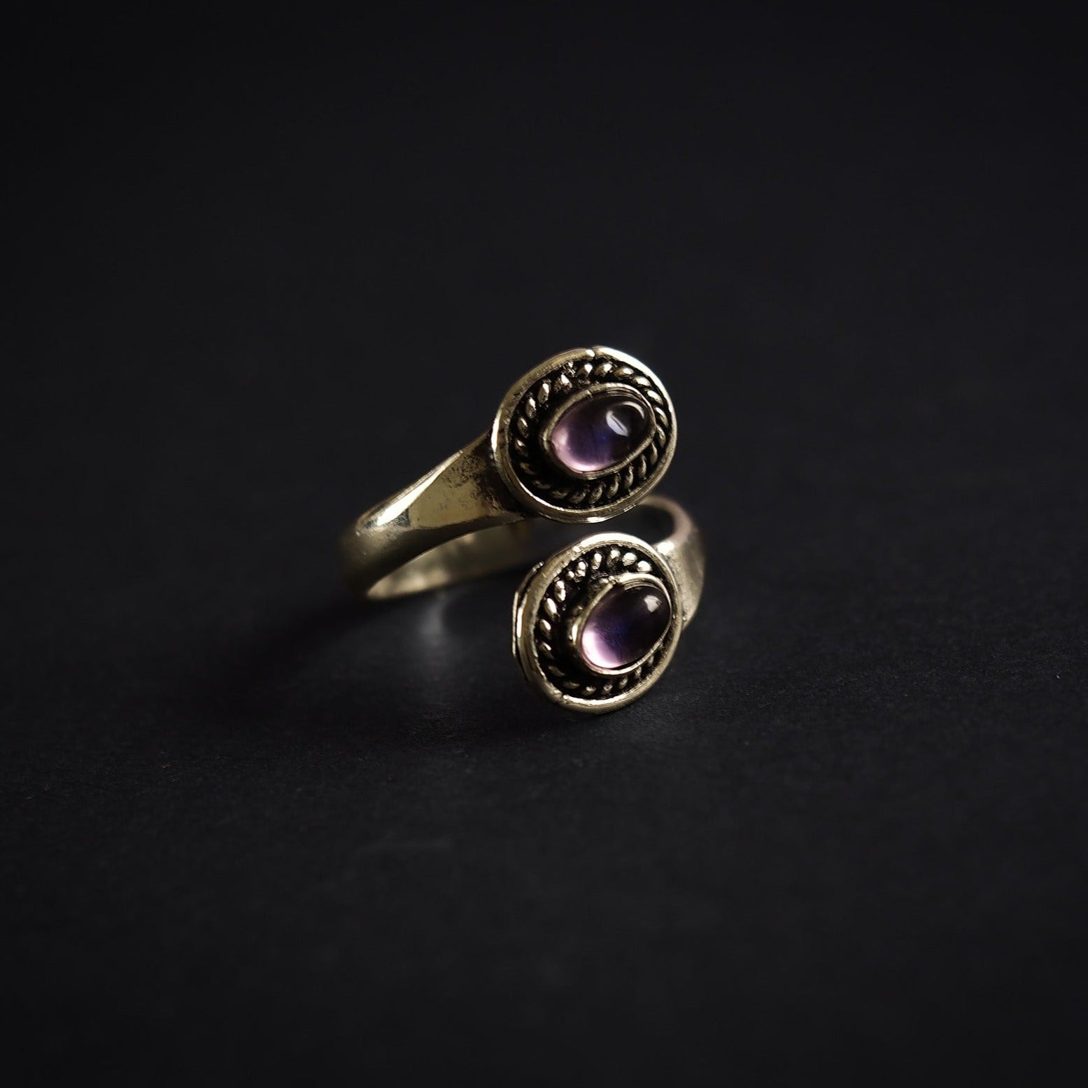 Närbild på adjustierbar spiralring i silverpläterad mässing med två lila ametister och dekorativ flätat kantmönster.