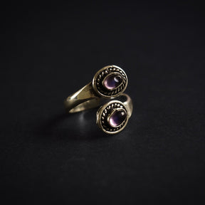 Närbild på adjustierbar spiralring i silverpläterad mässing med två lila ametister och dekorativ flätat kantmönster.