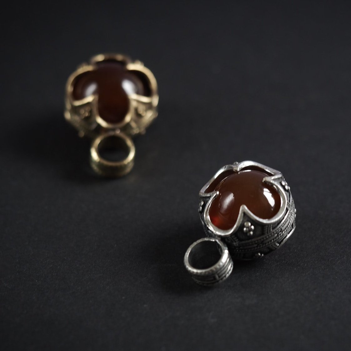 Två Gotlandshängen med karneol i silverpläterad och mässingsvarianter, vikingatida ornament synliga