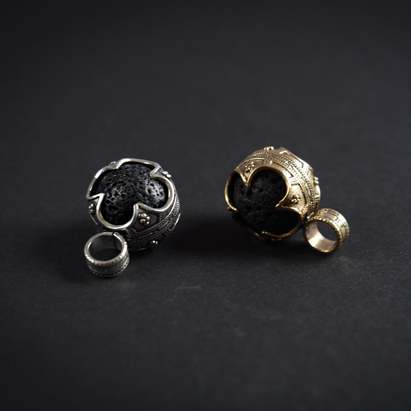 Jämförelse av två Gotlandshänge-varianter: en silverpläterad och en i mässing/guldton, båda med svart lavasten och vikingainspirerad design.