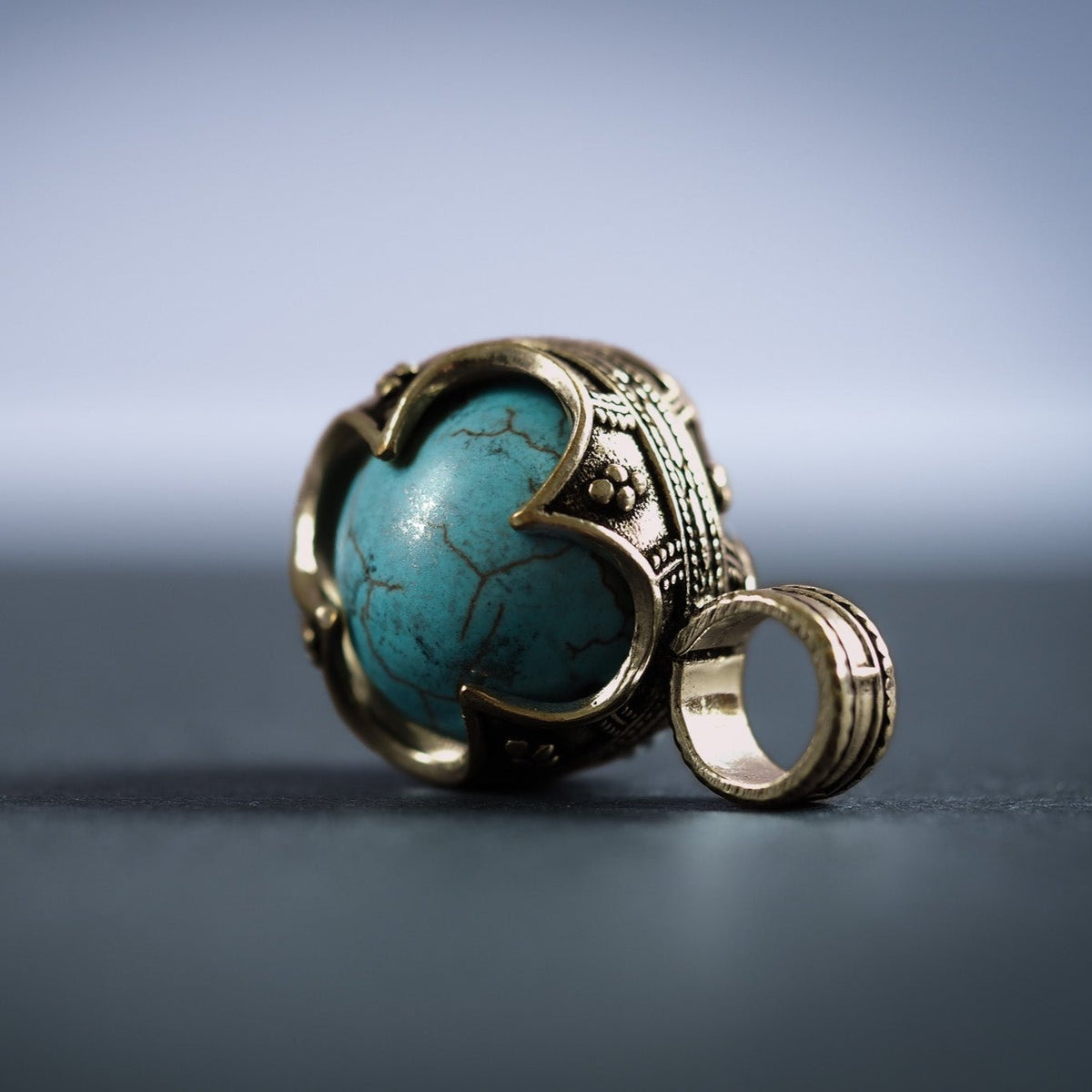 Två gotländska mässinghängen med turkos-stenar, visar ornamental metallram och stenens naturliga ådring