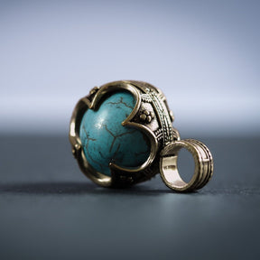 Två gotländska mässinghängen med turkos-stenar, visar ornamental metallram och stenens naturliga ådring