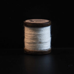 Naturvit brodyrtråd i 100% ull på träspole. Traditionell spole med mörkbetsad träram, cirka 50 meter tråd. Handarbetsmaterial för broderi och nålarbete.