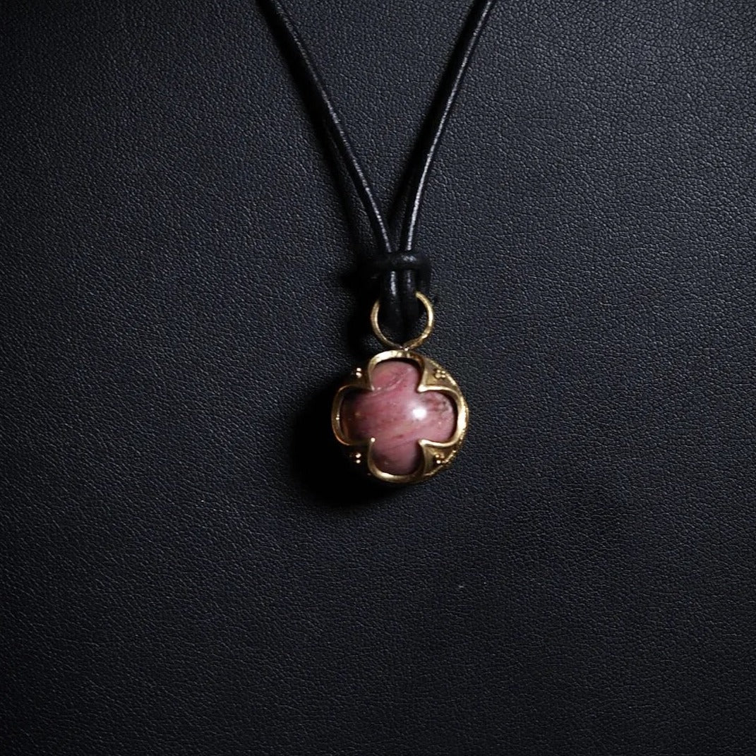 Gotlandshänge i brons med rosa jordgubbsagat hängande på svart läderrem mot mörk bakgrund