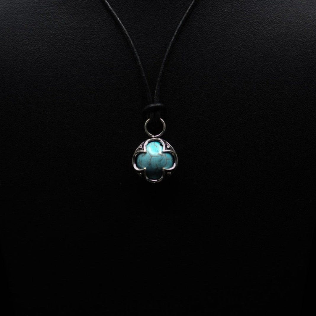 Turkoshängsmycke sett från under. Mässingsfattningen är fyrledad med keltiska knutverk. Stenen visar naturliga sprickornament karakteristiska för turkos.