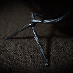 Närbild av järnsmide-stativ för dryckeshorn, visar tredelade ben och handsmedad textur