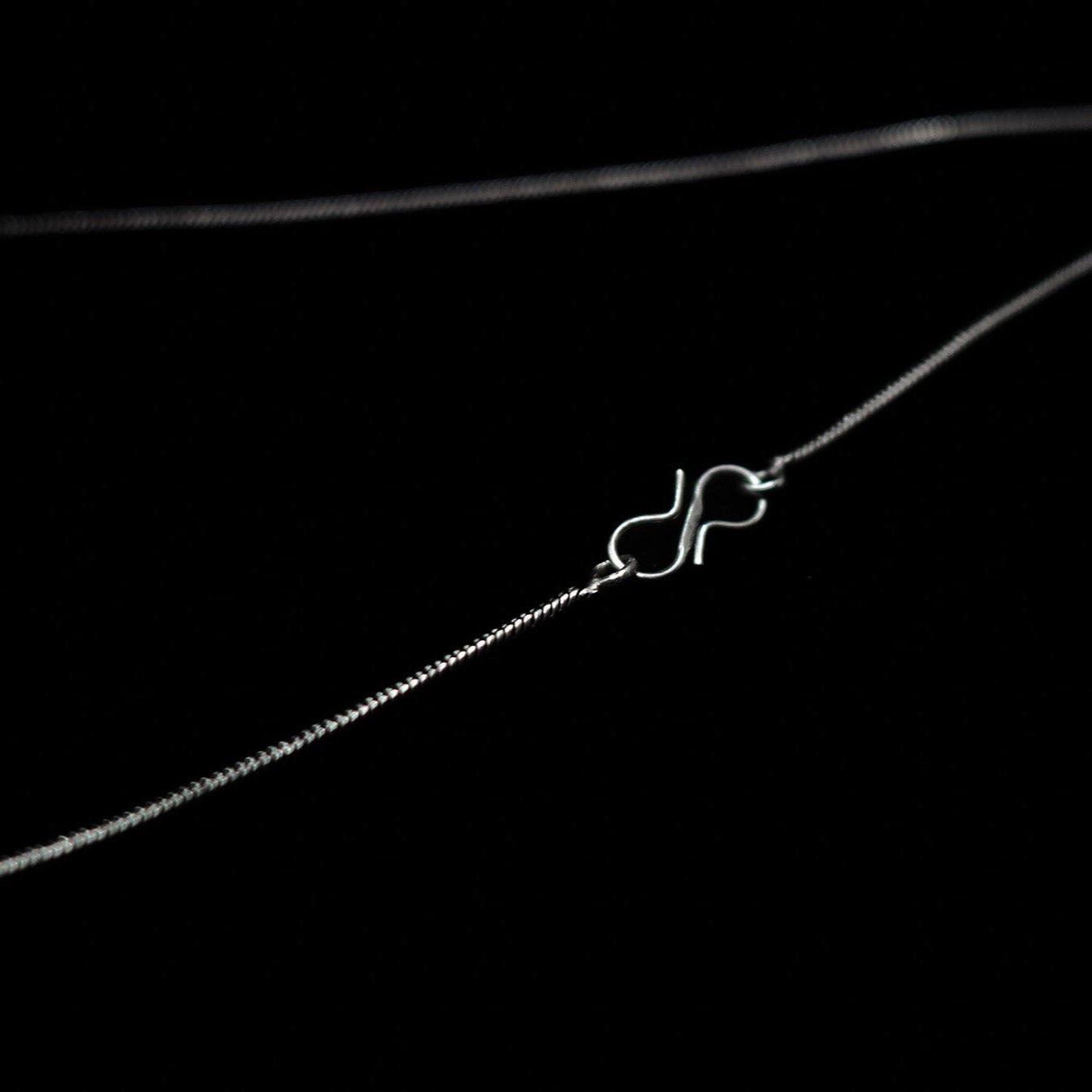 Detaljbild av silverpläterad kedjans s-formade lås, visar höggkvalitativ metalltillverkning lämplig för halsband även för barn