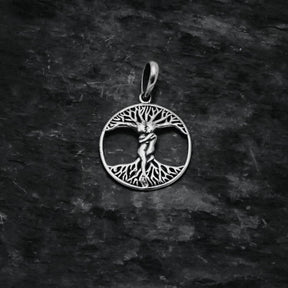 Träd-amulett fotograferad framifrån mot mörkgrå bakgrund, visar Yggdrasil-motivet med utstrålande grenar och rötter.