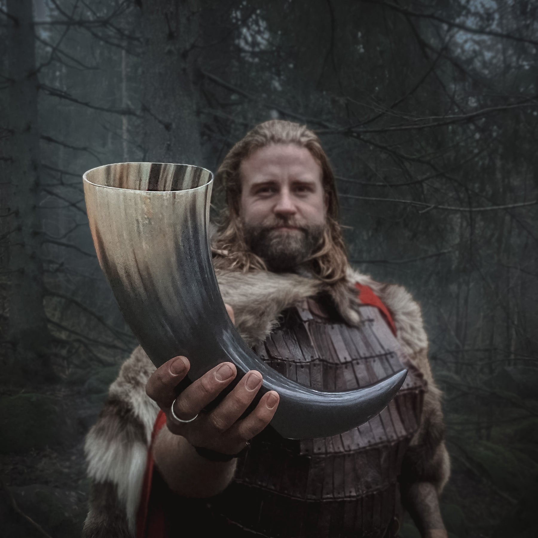 Stor dryckeshorn på ca 800ml, hållen av en Viking-klädd man i skogsmiljö, visar autentisk användning av hornbägaren
