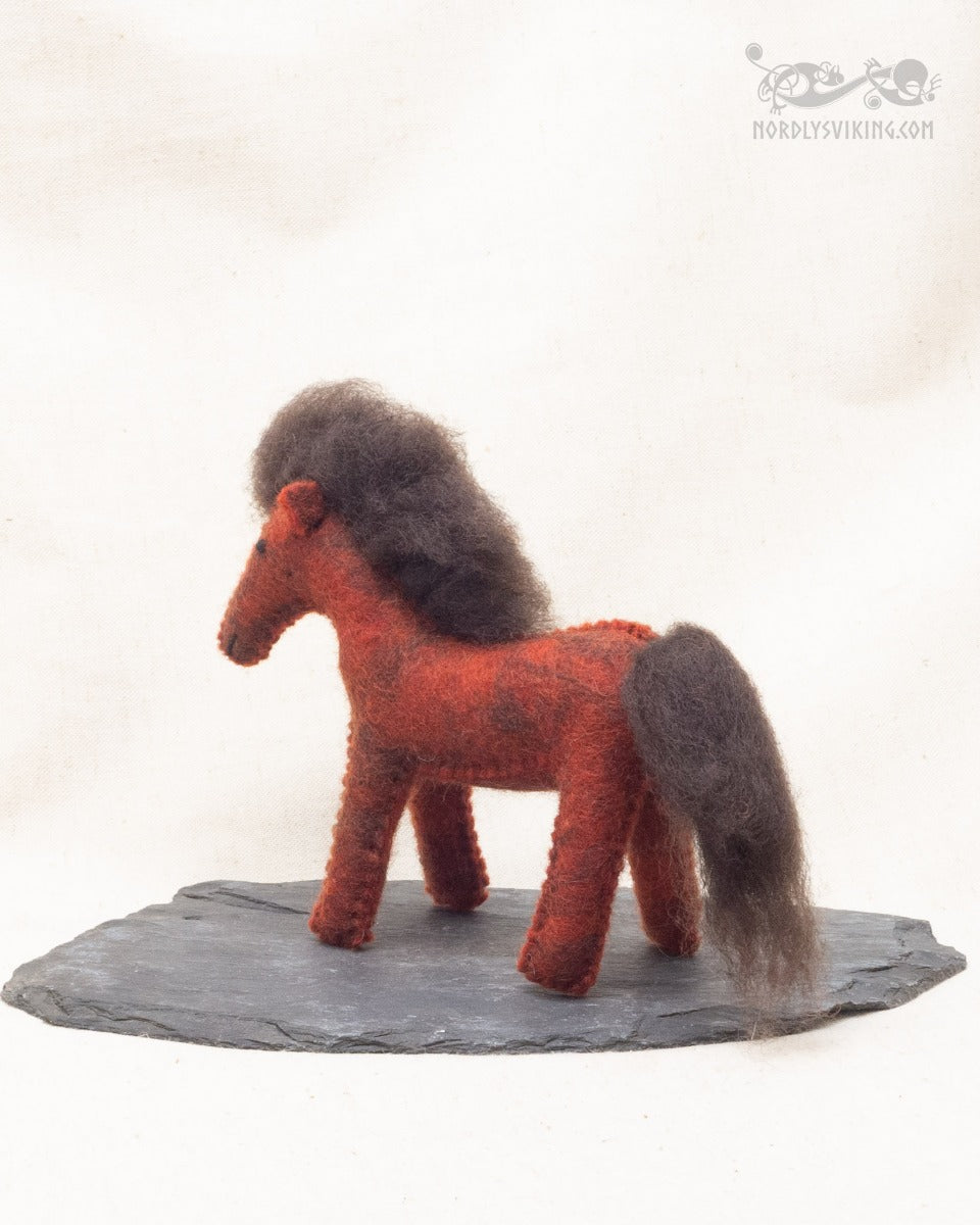 Handtovad rödbrun ullhäst med mörk man och svans, sidovy från vänster på skifferplatta