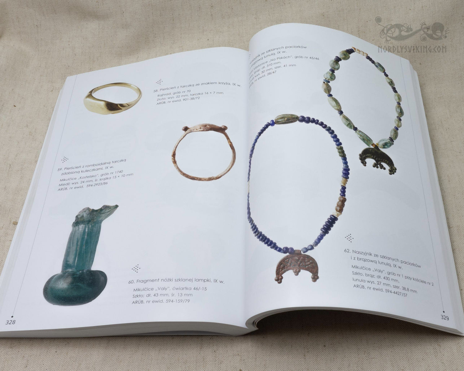 Museikatalog visar vikingtida halsband med blå och ljusa pärlor, guldringar och dekorativ älskhuvud-hänge från arkeologiska fynd.
