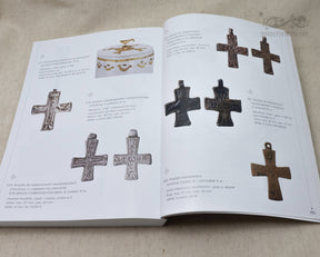 Museikatalog visar medeltida religiösa artefakter inklusive smidda kors, reliefskulpterade mässingsornament och dekorativa broschfibulor med lapislazuli-inlägg.