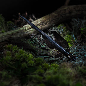 Nålbindingsnål i horn, svartfärgad organisk hornmaterial omkring 10 cm långt med traditionell design och ögla