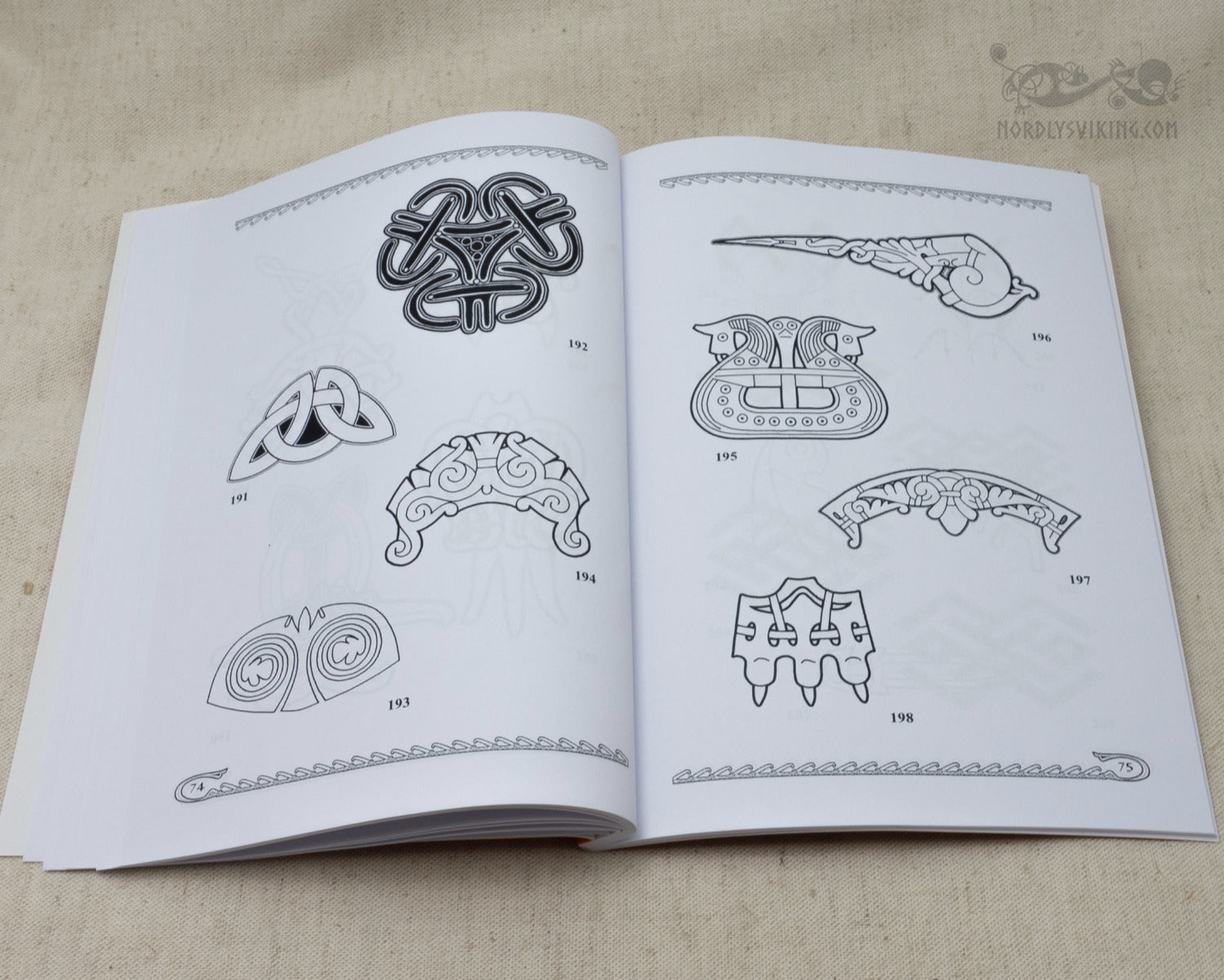Book page displaying Viking ornamental designs focused on brooches, collars, and interlocking knotwork patterns rendered as detailed black line drawings